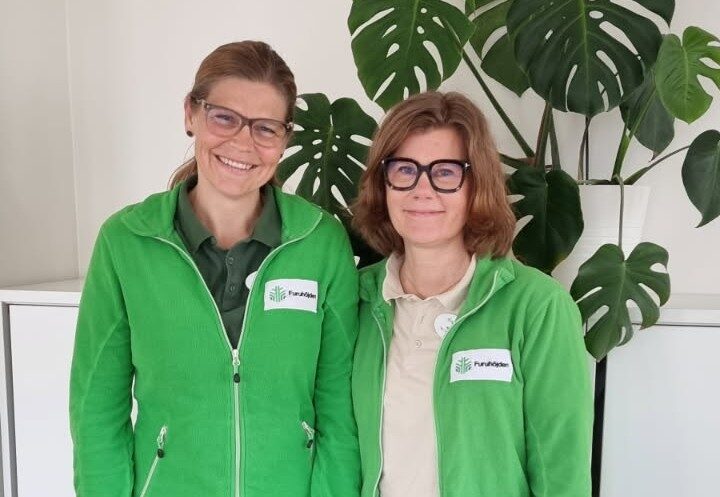 Fysioterapeuterna Åsa och Helena står bredvid varandra och ler in i kameran.